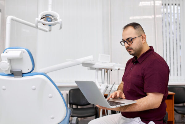 IT Support for Dental Offices in Glendale › TECHBLEED Man using a laptop beside a dental chair in a dental office